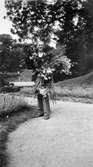Charles Gunnehed (född Johansson) bär ett fång med blommor.
Troligtvis arbetade han på Gunnebo slott. Gunnebo slottspark 1930-tal.