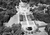 Flygfoto från söder på Gunnebo slott. Man ser trädgårdsdammen, södra trädgården, huvudbyggnaden och norra trädgården i bakgrunden. 1960-70-tal.