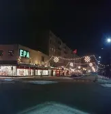 Adventsbelysning på Kungsgatan i Huskvarna. Till vänster ligger varuhuset EPA med upplysta skyltfönster.