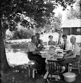 Hjärttorp utanför Jönköping. Gruppbild av människor vid festligt tillfälle, ute vid Tords klubbstuga. Från vänster 1. Norbert Fridh. 2. Ture Nilsson med Jan-Åke Nilsson i knät. 3. Alice Sandahl. 4. Majken Nilsson. 5. Erhard Johansson. 6. Åke Sandahl. 7. Bengt Sandahl (längst fram).