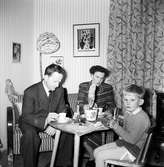 Familjen Andersson, Evert, Elin och sonen Tom, sitter runt ett bord och fikar vid juletid.