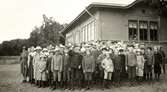 Elever och lärare står utanför gymnastiksalen/samlingssalen vid Kålleredsskolan cirka 1920.