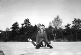 Birgitta och Christina åker skridskor men ligger nu på Färås tjärn/Bergsjöns is i Kållered, år 1961.