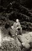 Carl Krantz (1880 - 1956) och eleven Filip sitter utomhus omgiven av grönska, Stretered 1930-tal. Carl arbetade som skomakare och undervisade funktionshindrade personer på Stretereds skolhem/vårdhem.
