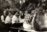 Stretered vårdhems personal, som nyss har ätit, sitter vid ett uppdukat bord utomhus i Slagsta (Botkyrka kommun) år 1936. Från vänster: herr Hellborn, syster Gurli, dold kvinna, fröken Ahlin, direktör Fryklund, Carl Krantz, två danskar och en norrman.