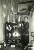 Fru Jönsson står på bottenvåningen i rektorsvillan, år 1926. Anna Jönsson var husmor och kallades 