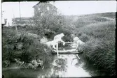 Vittinge sn, Heby kn, Vittinge.
Tre kvinnor tvättar. I bakgrunden syns ett hus som tillhörde frälsningsarmén. 1920-talet.