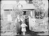 Familj vid staketet med bostadshuset i bakgrunden, Östhammar Uppland