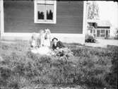 Familj i trädgården med bostadshuset i bakgrunden, Östhammar Uppland