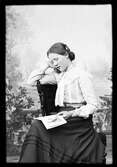 Ateljéporträtt - Ruth Skötsner sitter och läser i en bok, Östhammar Uppland 1903