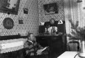 Fotograf Gustav Andersson sitter i soffan och läser tidningen.
