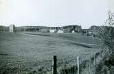 Tulebo år 1951. Vy nerifrån Tulebosjön, upp emot transformatorstationen till vänster och de två personalbostäderna till höger. Det högra bostadshuset (Tulebovägen 23-27) stod färdigbyggt 1921. Det lilla huset längst till höger är en tillhörande vedbod. Det vänstra av de tre husen är 