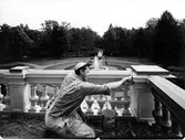 En man målar verandan på Nolhaga slott sommaren 1963.