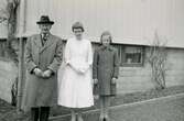 Konfirmation för Eva Pettersson (född 1944, gift Kempe) som står finklädd på tomten tillsammans med farfar Oscar Pettersson och lillasyster Karin (född 1947, gift Hansson) på Gamlehagsvägen 17 i Torrekulla år 1958.