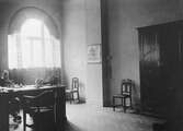 Jönköpings högre allmänna läroverk. En man sitter vid sitt skrivbord. Ett stort skåp står vid ena väggen och ljuset faller in över rummet från ett stort fönster.