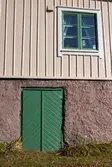Våmmedal i Kållered den 6 oktober 2016. Detalj av södra fasaden till bostadshuset Streteredsvägen 7. En grön källardörr samt ett fönster.