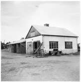 Vägstation C5, Rasbo. Verkstads- och garagebyggnad. Diverse skrot mm framför garaget, bland annat tandat hyvelstål.