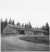 Vägstation C7, Skärplinge. Byggnad med verkstad, kontorsdel, garage. Uppfartsväg och stängsel med grind. Liten lastbil (paketbil) framför verkstaden. Personbilar framför garaget. Spetsplog.
