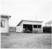 Vägstation D7, Jönåker. Liten förrådsbyggnad. Framför byggnaden cyklar och en motorcykel. På gaveln manskapsskåp, där de anställda förvarade personliga ägodelar inklusive handredskap.