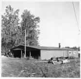 Vägstation D8, Sandstugan, filial Bettna. Garage- och förrådsbyggnad. Öppen gavel till förrådsdelningen. Vägsladd.