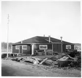 Vägstation D9, Vagnhärad. Garage- och förrådsbyggnad. Cirkelsåg och upplag av ved.