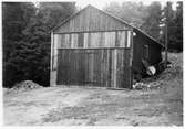 Vägstation D9, Vagnhärad, filial Tystberga. Garagebyggnad, med port på gaveln, delvis inbyggd i slänt. Slipstensbock till höger.