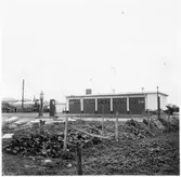 Vägstation Vmo E3, Boxholm, filial Ödeshög. Garagebyggnad. Personbil parkerad på garageplan. Bensinpumpar (drivmedelspumpar) bland annat troligtvis Ljungmans pump (till höger) Star, 1950.