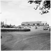 Vägstation E4, Rimforsa. Garagebyggnad med förråd på övervåning. Personbil. Bensinpumpar (drivmedelspumpar). Grussorteringsverk till vänster.