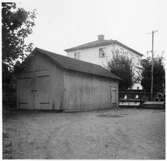 Vägstation E11, Motala, filial Berg. Garage- eller förrådsbyggnad, med portar på gaveln. Bostadshus i bakgrunden.