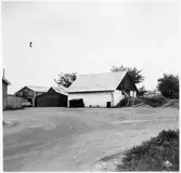 Vägstation E12, Tjällmo. Filial Borensberg. Förrådsbyggnad och garagebyggnad. Cykelkärra framför förrådsbyggnaden.