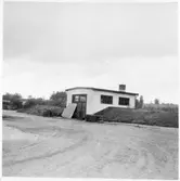 Vägstation G2, Berghem. Förrådsbyggnad. Diverse materiel utanför byggnad. Sandspridaren (sandningsmaskin) Åsbrink, typ SS.