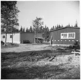 Vägstation G3, Vislanda. Förrådsbyggnad (gaveln) och garagebyggnaden (gaveln). Vid gaveln på garagebyggnaden cykelställ med cyklar, sandspridare.