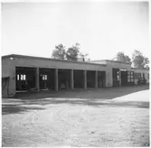 Vägstation G3, Vislanda. Portarna till garagen öppna. Några personbilar inne i garaget. Framför verkstadsdelen en liten lastbil (paketbil).