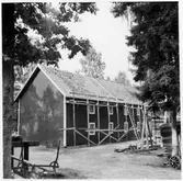 Vägstation G7, Ingelstad. Förrådsbyggnad i två våningar. Arbete pågår med nytt tegeltak, byggnadsställningar på framsidan. Vägsladd till vänster.