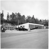 Vägstation H2, Gamleby. Garagebyggnad, invid väg. Uppställda sidoplogar och spetsplogar. En sidoplog märkt 