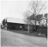 Vägstation H4, Hjorted. Förrådsbyggnad. Upplag av diverse material, cementrör, muffrör.  Liten godspall med trälådor, invid väg.