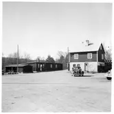 Vägstation L3, Örkelljunga. Bostadshus, eventuellt tjänstebostad för vägmästaren, byggnad till vänster kontors- eller rastlokal för vägarbetarna, två manspersoner vid dörren. Öppet skjul med cykelställ med cyklar. Personbil på garageplan.