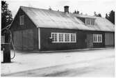 Vägstation L4, Hässleholm. Byggnad med garagedel, portar på gaveln, och långsidan. Bensinpump (drivmedelspump).
