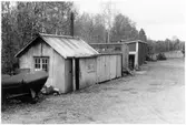 Vägstation N3, Kvibille, filial Torup. Små förrådsbyggnader. En byggnad med skorsten, eventuellt manskapets raststuga. Manskapsvagn mellan byggnaderna, rök från skorstenen indikerar även denna som raststuga för manskapet. Spetsplog till vänster, märkt 