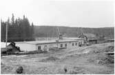 Vägstation P16, Bengtsfors. Vägstationens huvudbyggnad med verkstad, kontor och garage (baksidan). Markberedning pågår. Decauvillevagnar. Bortom denna byggnad äldre byggnad med skylt på framsidan 