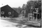 Vägstation S2, Molkom, filial Skattkärr. Förrådsbyggnad (gaveln). Vid gaveln upplag av vägmärken, bland annat vägmärke 