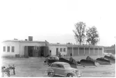 Vägstation S6, Torsby. Vägstationens huvudbyggnad med från vänster verkstad, kontor, garage. På garageplan spetsplogar och två personbilar, varav en Volvo PV.