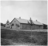 Vägstation T4, Svartå, filial Vretstorp. Garagebyggnad. I bakgrunden förrådsbyggnad. Bensinpump (drivmedelspump), vattentunna av trä.