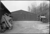 Vägstation T5, Ånstaberg. Garagebyggnad, i bakgrunden. Till vänster förrådsbyggnad. Uppställda mot väggen sandspridare, typ 