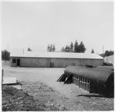 Vägstation T8, Grythyttan. Garagebyggnad. I förgrunden två oljecisterner.