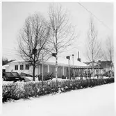 Vägstation U6, Anundshög. Garagebyggnad. I förgrunden sandspridare. Cykelställ med cyklar. Anläggningen innanför nätstängsel. Bostadshus i bakgrunden.