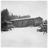 Vägstation U6, Anundshög. Förrådsbyggnad. Stora behållare (tunnor) uppställda på bockar, eventuellt för drivmedel.