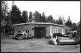 Vägstation W 6, Falun. Vägstationens huvudbyggnad med verkstad, kontor och garage. Olika väghållningsmaskiner uppställda framför byggnaden, bland annat sandspridare och diverse 