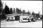 Vägstation W 6, Falun. Vägstationens huvudbyggnad med verkstad, kontor och garage. Olika väghållningsmaskiner uppställda framför byggnaden, bland annat sandspridare och diverse 