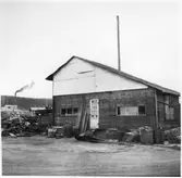 Vägstation Vmo X4, Bollnäs. Förrådsbyggnad med diverse skrot framför.